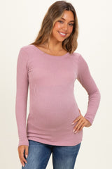 woman wearing a light pink long sleeve ribbed maternity top and showing her baby bump