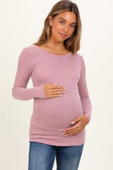 woman wearing a pink ribbed long sleeve maternity top and holding her baby bump