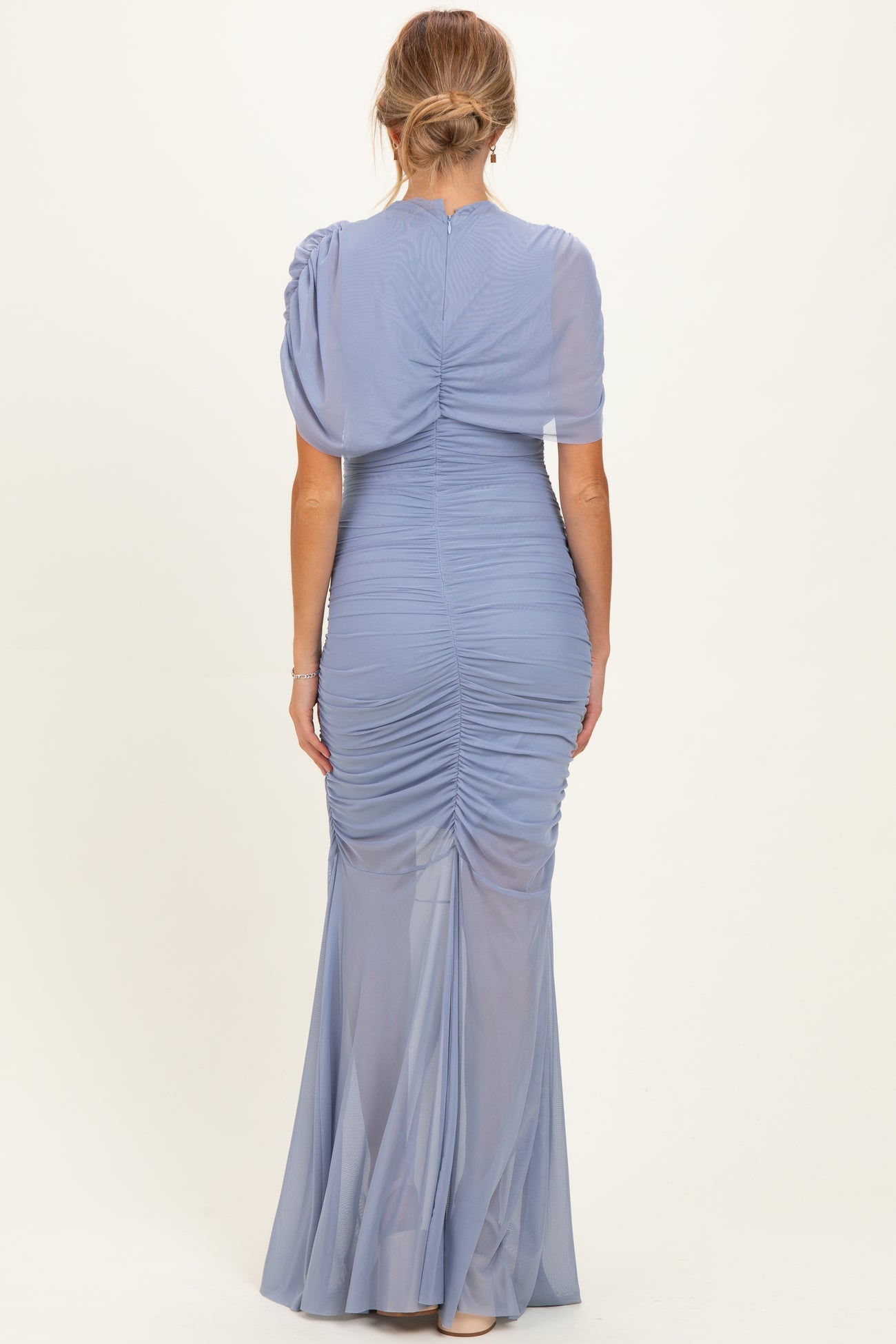 woman wearing a soft blue maternity gown with a fitted ruched design and short puff sleeves, seen from the back