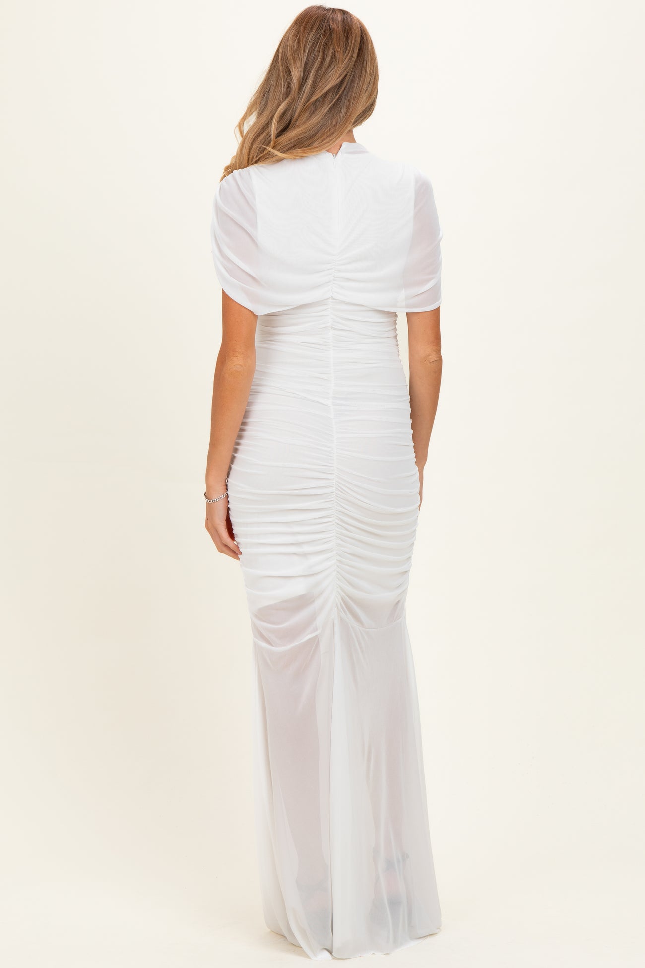 woman wearing a white maternity dress with back ruching and short sleeves, showing off a baby bump