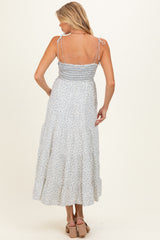 woman wearing a light blue floral maternity maxi dress with adjustable straps and a smocked back