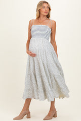 woman wearing a light blue floral maternity dress with smocked bodice and spaghetti straps, showing her baby bump