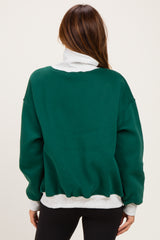 woman wearing a green oversized sweatshirt with a white collar and hem, shown from the back