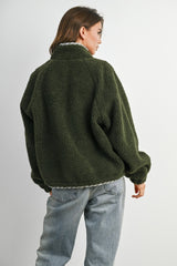 woman wearing a green oversized fleece jacket and light blue jeans, viewed from the back