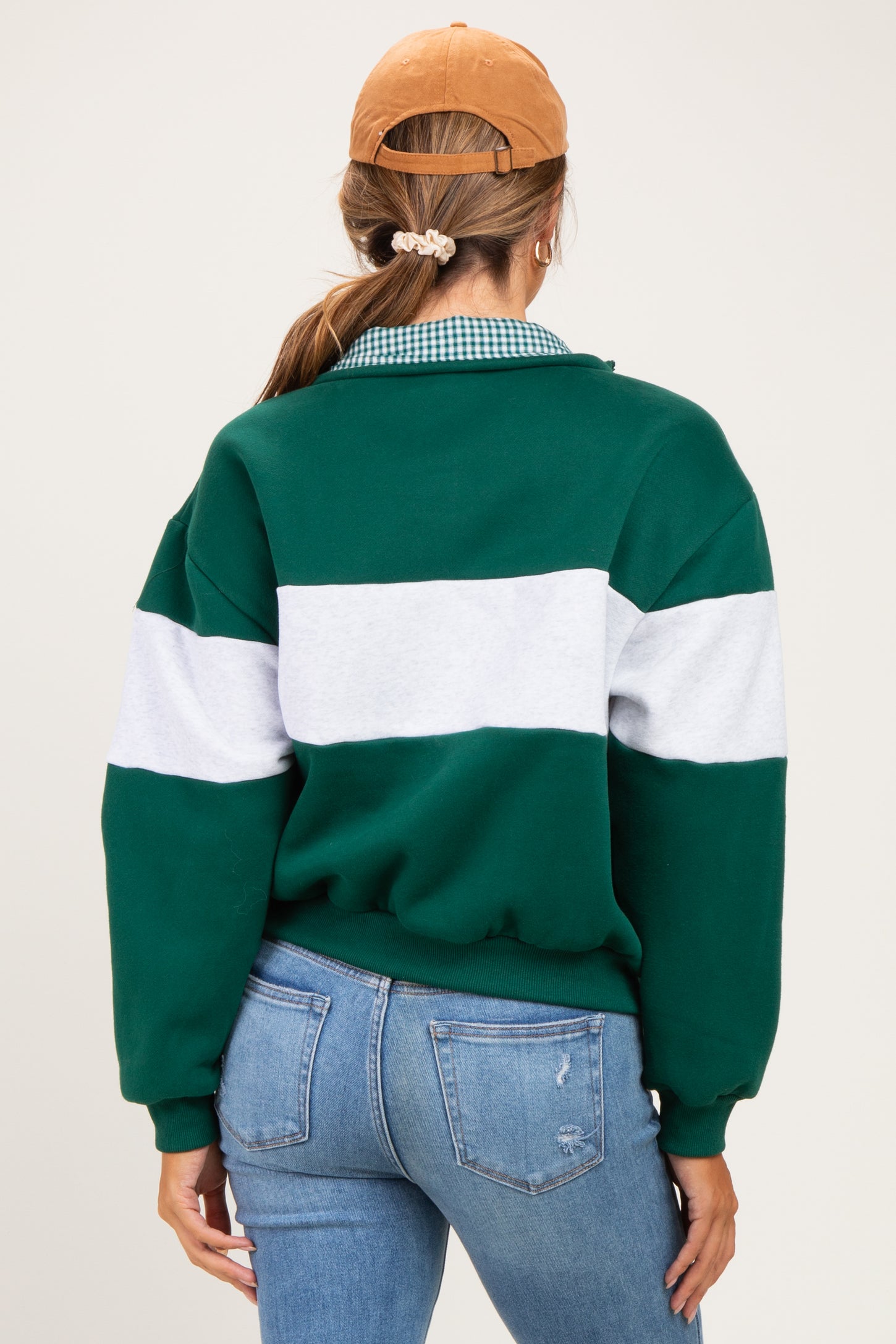 woman wearing a green and gray colorblock maternity sweatshirt with a relaxed fit and tied back hair