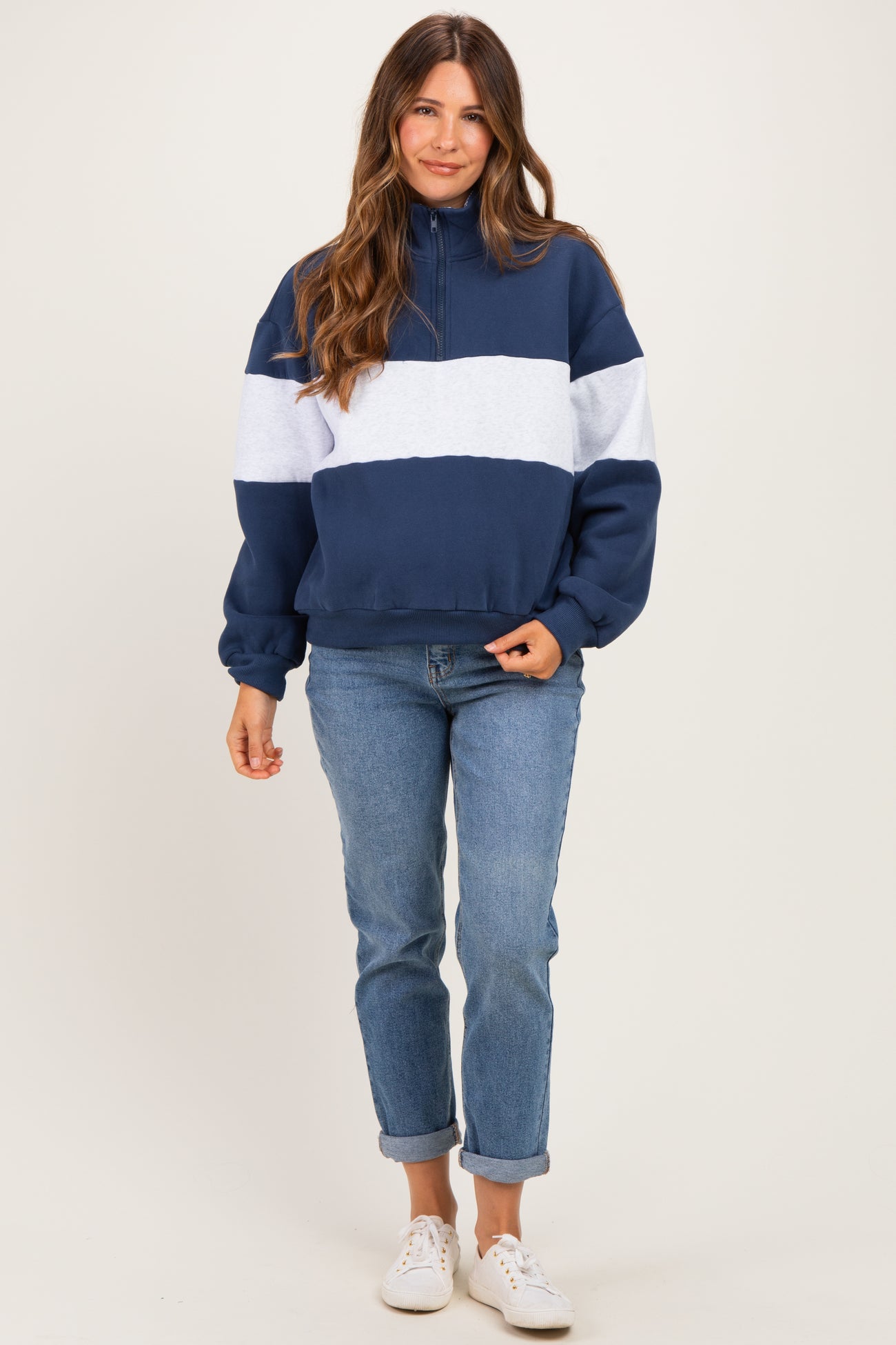 woman wearing a navy blue and light gray color block maternity hoodie and relaxed fit jeans