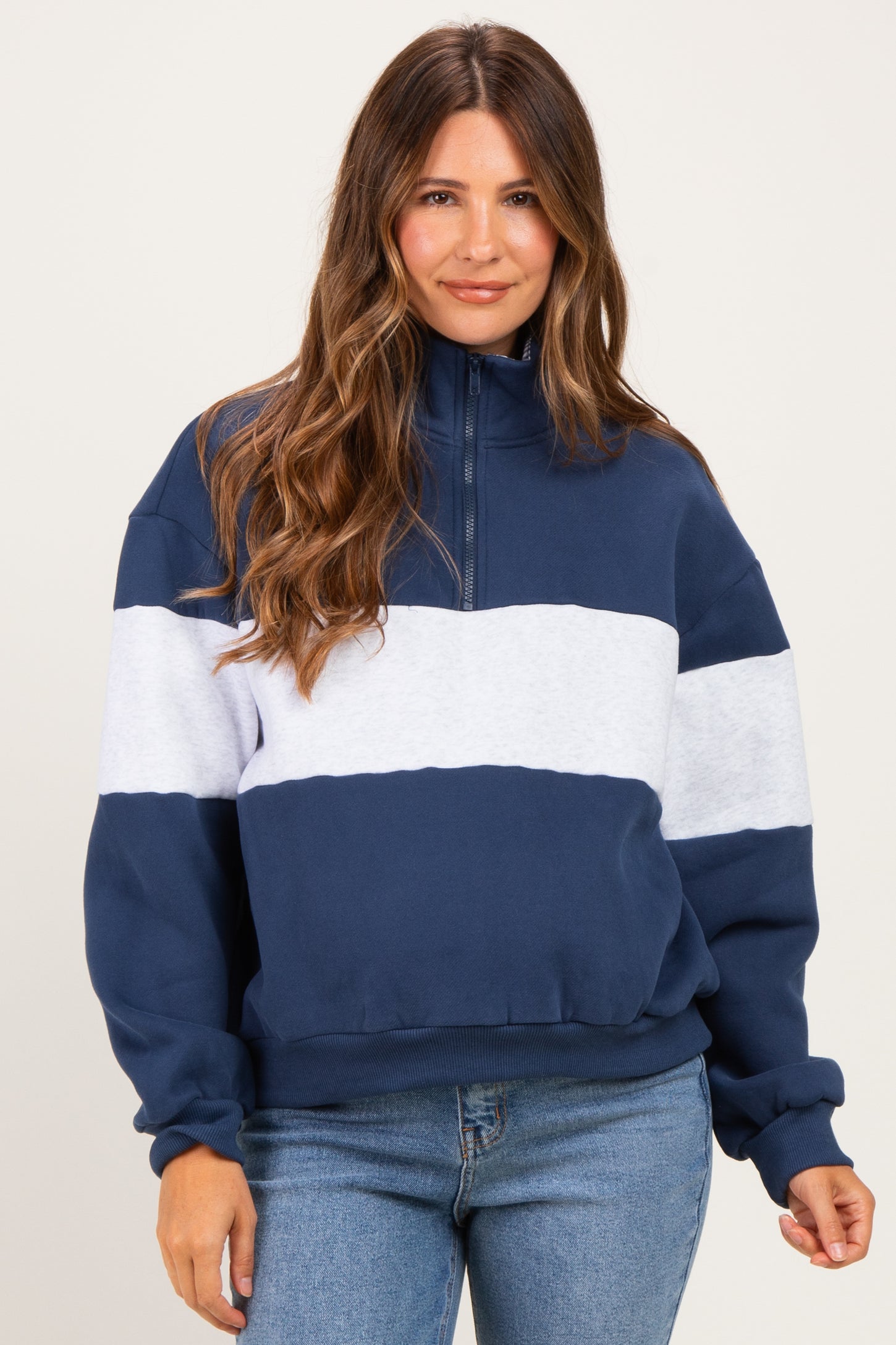 woman wearing a navy and light blue color-blocked maternity pullover sweatshirt with a quarter zip