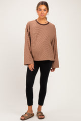 woman wearing a brown long sleeve maternity top with a relaxed fit and black leggings