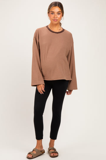 woman wearing a brown long sleeve maternity top with a relaxed fit and black leggings