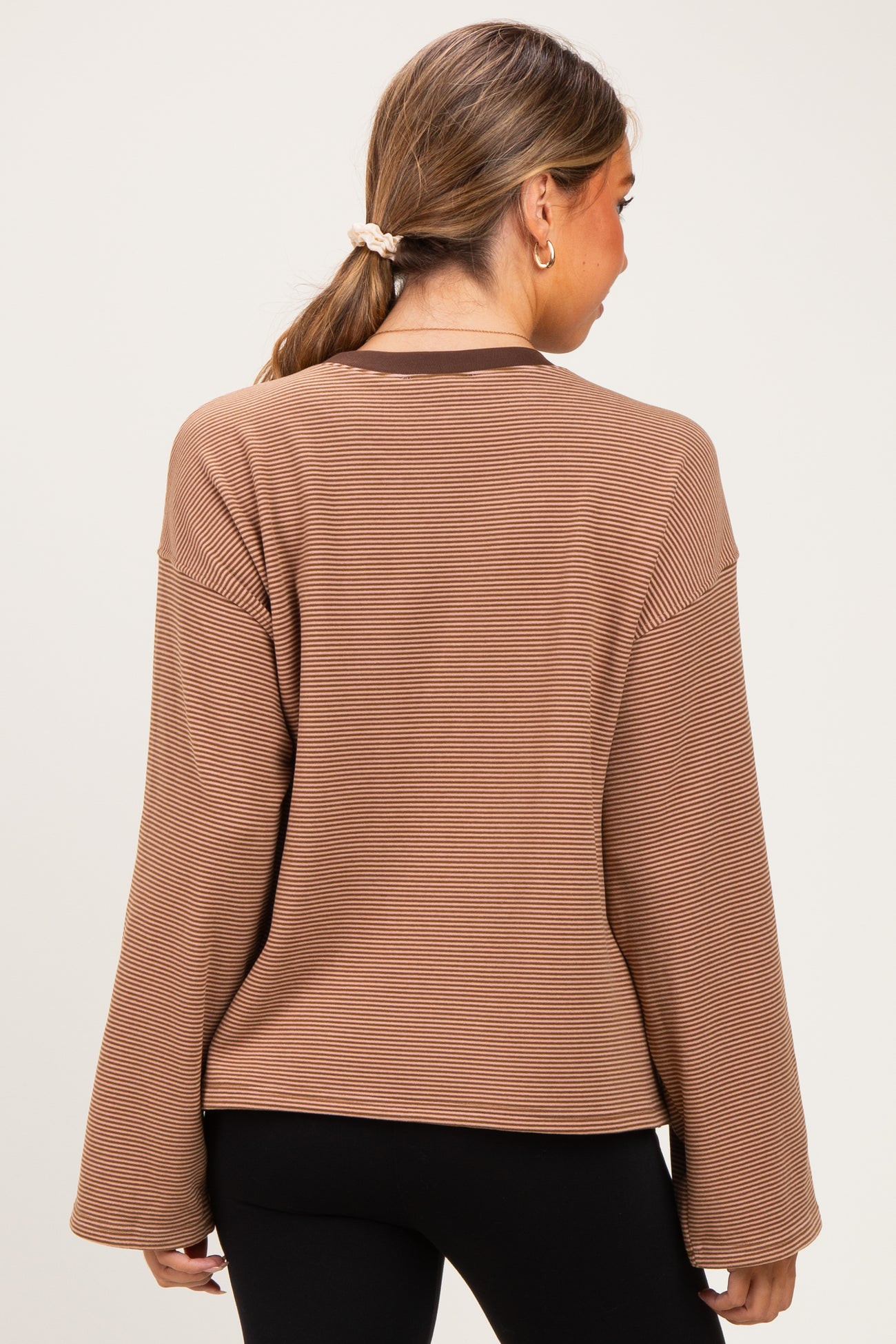 woman wearing a brown striped maternity top with wide sleeves, showing the back view