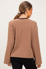 woman wearing a brown striped maternity top with wide sleeves, showing the back view