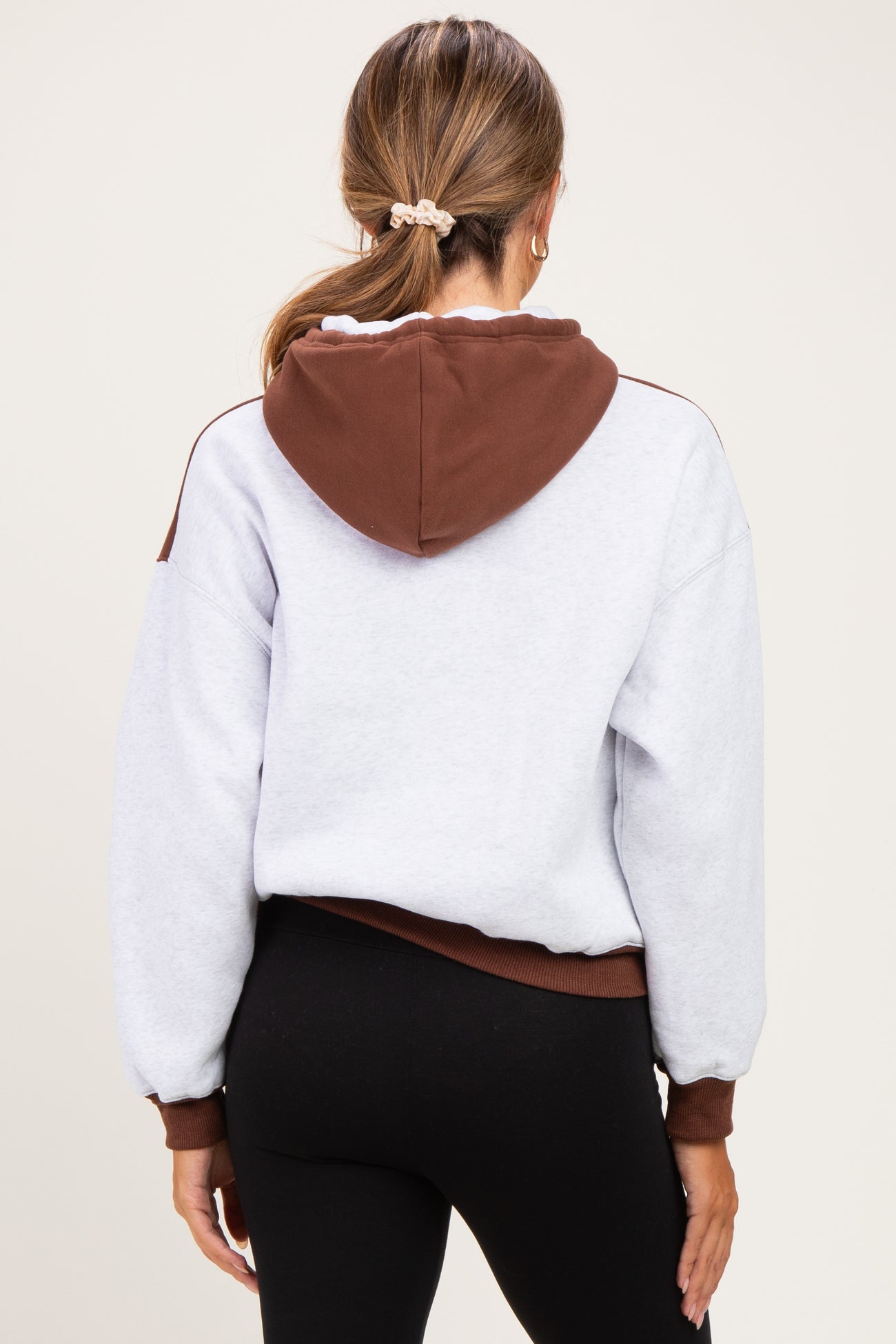 woman wearing a grey and brown color-block maternity hoodie with a relaxed fit and a hood