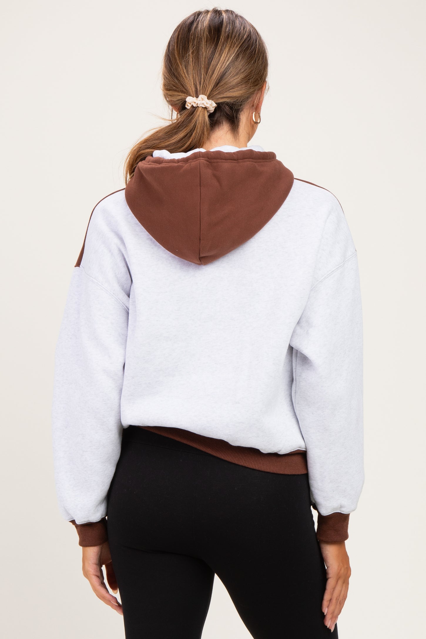 woman wearing a grey and brown color-block maternity hoodie with a relaxed fit and a hood