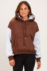 woman wearing a brown and gray color block hoodie with a front pocket and hood