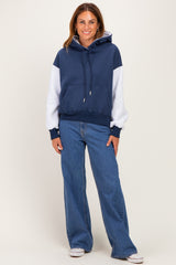 woman wearing a navy and gray color-block hoodie with a front pocket and blue wide-leg jeans