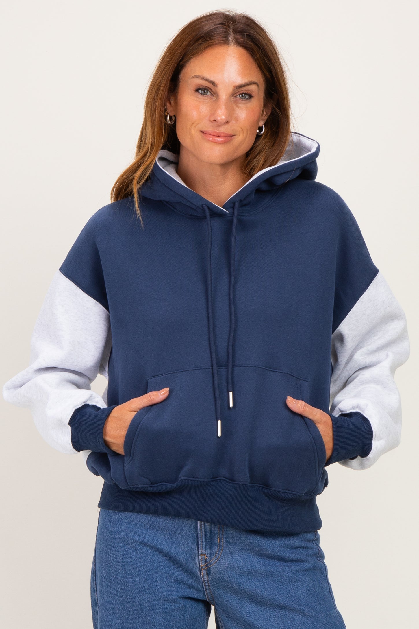woman wearing a navy and gray color block hoodie with a front pocket and drawstring hood