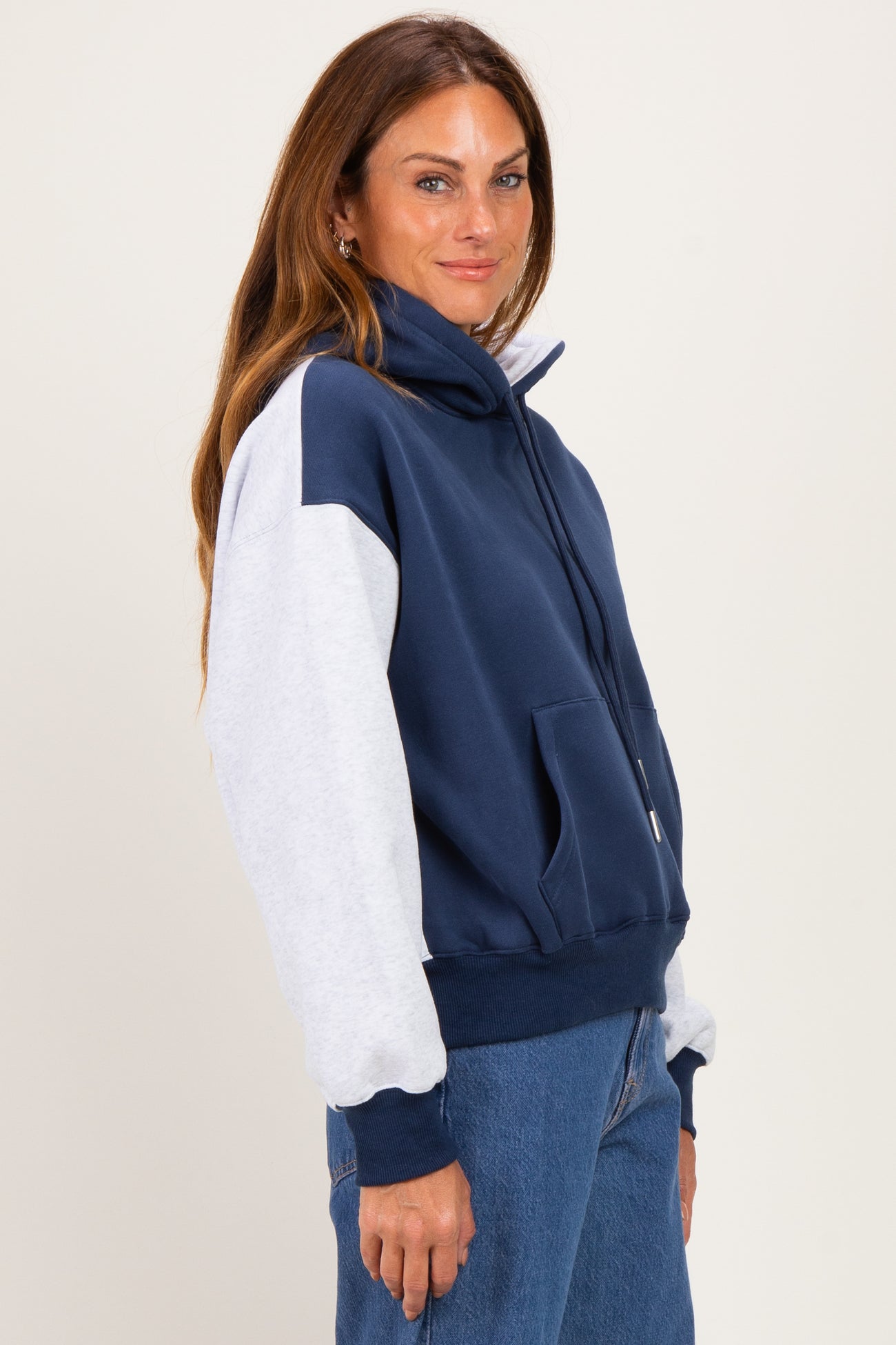 woman wearing a navy blue and light gray color block zip-up sweatshirt with a high collar and relaxed fit