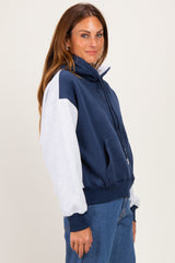 woman wearing a navy blue and light gray color block zip-up sweatshirt with a high collar and relaxed fit
