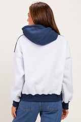 woman wearing a gray and navy hoodie with a cropped fit and ribbed cuffs, seen from the back