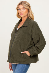 woman wearing a dark green corduroy maternity jacket with a oversized fit and front pocket, displaying her baby bump