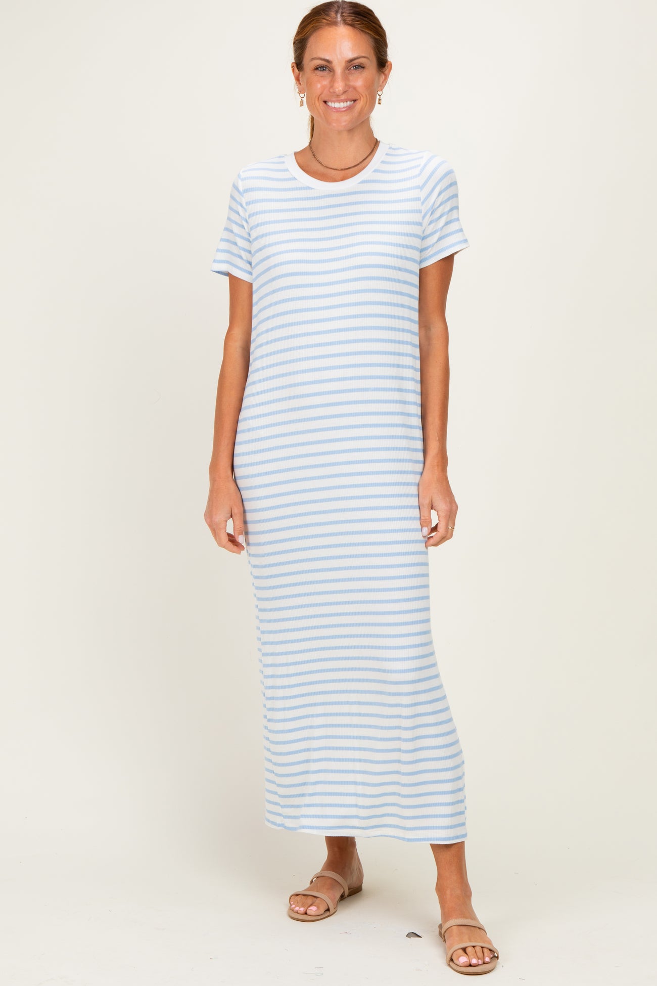woman wearing a light blue striped maxi dress with short sleeves and standing in a neutral background