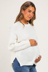 woman wearing a white knitted maternity sweater and holding her baby bump