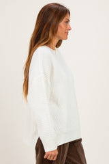 woman wearing a white oversized knit sweater with a textured pattern and side slits, model shown from the side