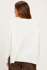 woman wearing a white knitted sweater, showing the back view with a relaxed fit and ribbed hem