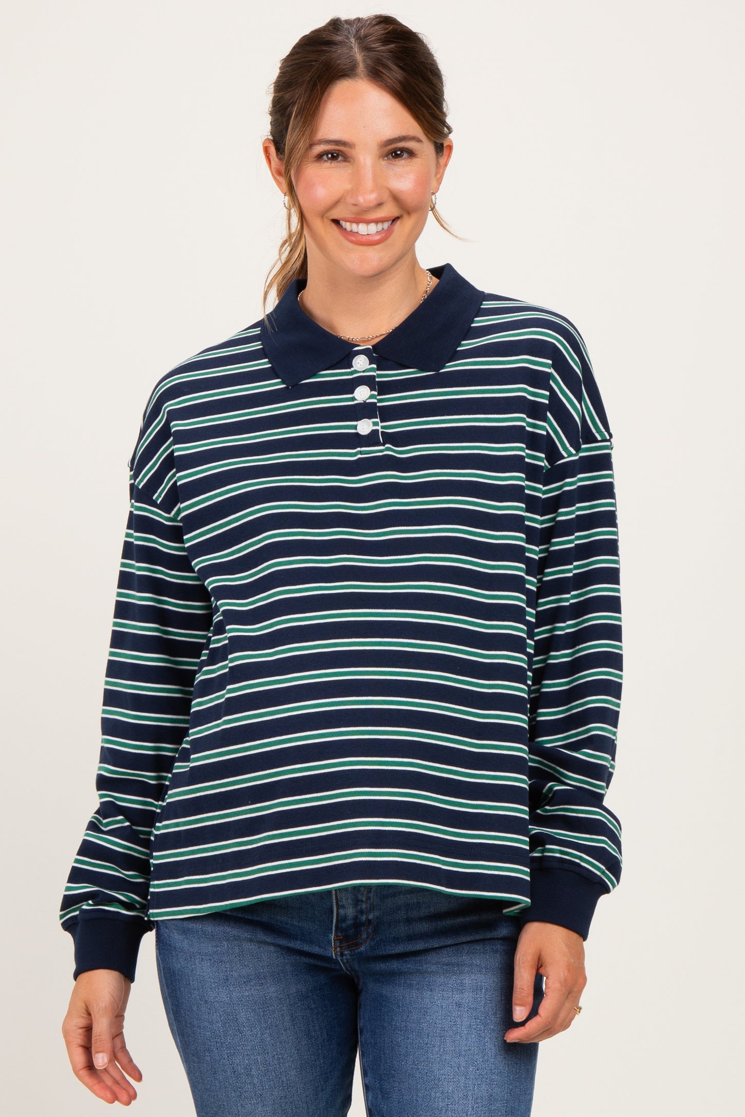 woman wearing a navy blue and green striped maternity polo shirt and smiling