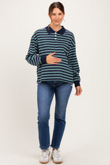 woman wearing a navy and green striped maternity polo shirt and blue jeans, holding her baby bump