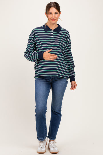 woman wearing a navy and green striped maternity polo shirt and blue jeans, holding her baby bump