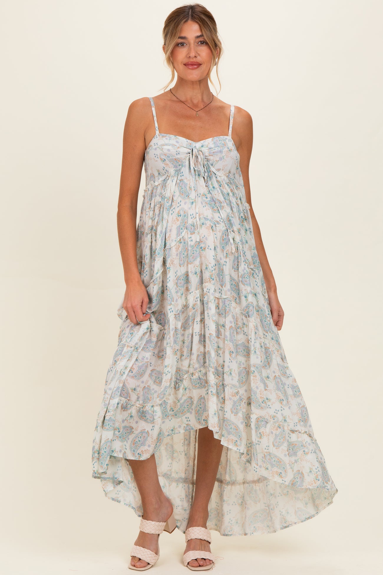 woman wearing a light blue floral maternity maxi dress with spaghetti straps and a flowy hem, showcasing her baby bump