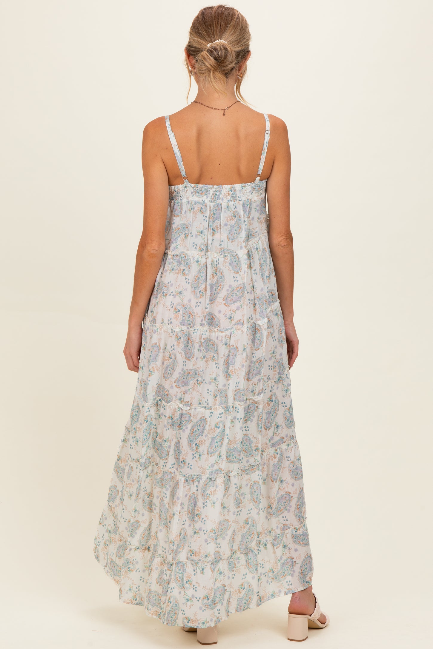 woman wearing a light floral maternity maxi dress with adjustable straps and a flowy silhouette, showing the back view