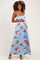woman wearing a light blue floral maternity maxi dress with a fitted bodice and adjustable straps, gently cradling her baby bump