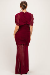 woman wearing a burgundy maternity dress with short sleeves and ruched details, showing a baby bump from the back