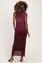 woman wearing a burgundy sleeveless maternity dress with a fitted silhouette and a long, sheer hemline