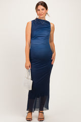 woman wearing a navy blue sleeveless maternity dress with ruching and a sheer bottom, holding a small white bag