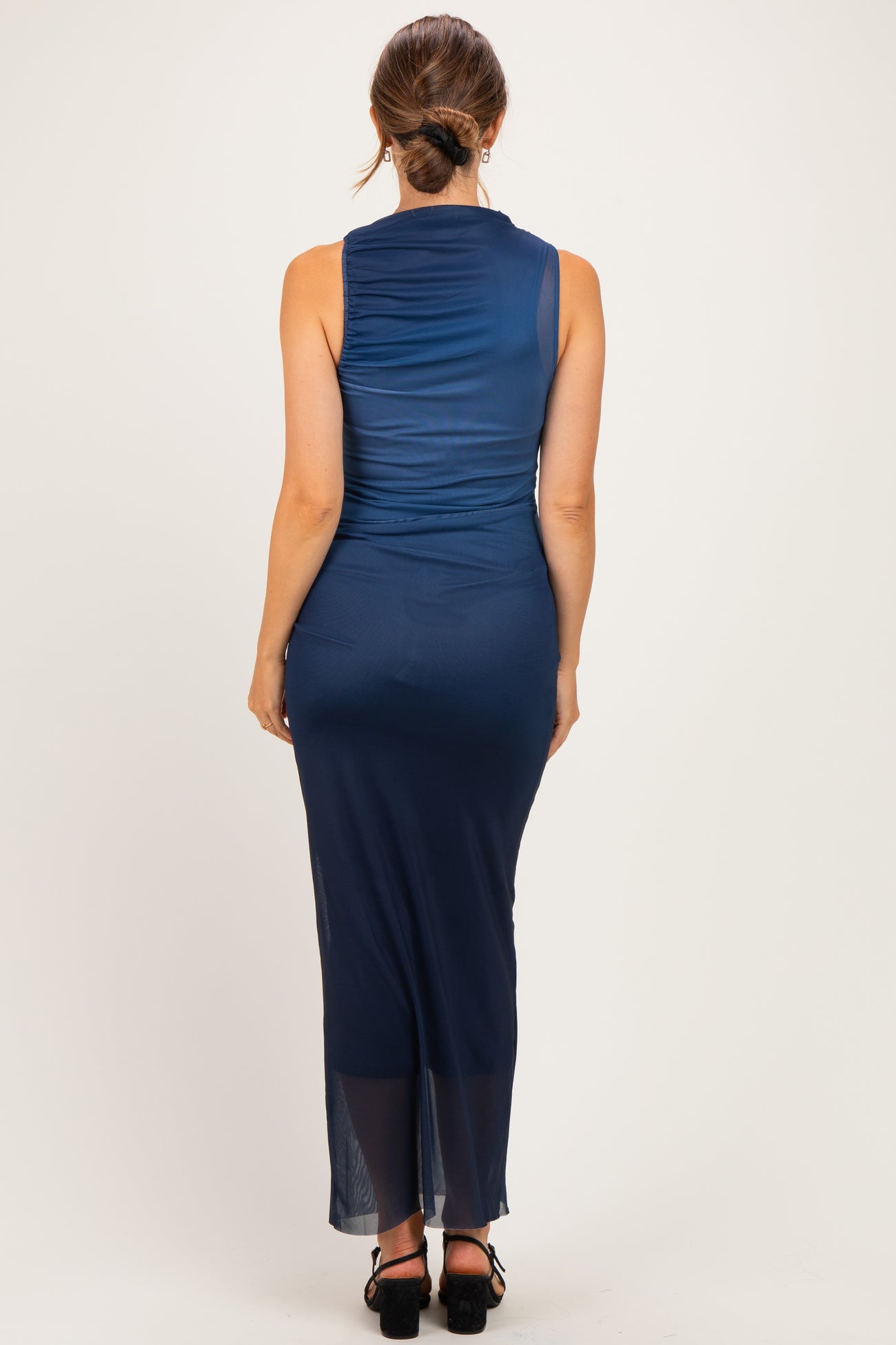 woman wearing a navy blue sleeveless maternity dress with a flowy silhouette, showing her baby bump from the back