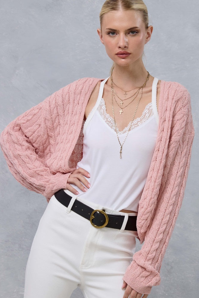 woman wearing a light pink cable knit cardigan over a white camisole and styled with white jeans and layered necklaces