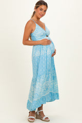 woman wearing a light blue maternity maxi dress with floral patterns and a visible baby bump