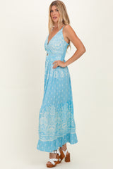 woman wearing a light blue floral maxi dress with a tiered skirt and a v-neckline, standing in profile