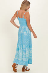 woman wearing a light blue floral maxi dress with spaghetti straps and tiered skirt, showcasing an open back