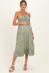 woman wearing a green floral strapless maternity maxi dress and holding her baby bump