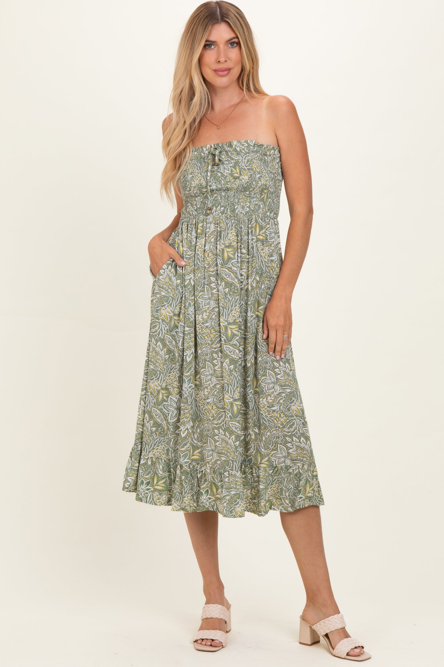 woman wearing a green strapless midi dress with a floral print and pockets
