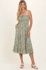 woman wearing a green strapless midi dress with a floral print and pockets