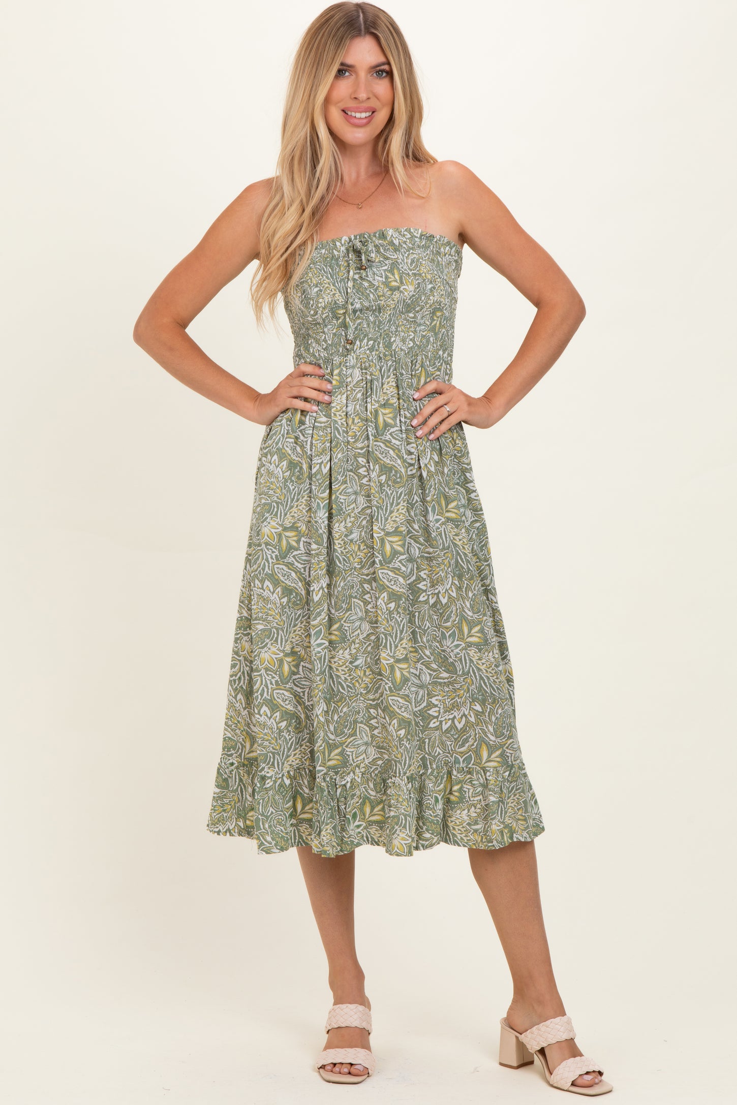 woman wearing a strapless green floral midi dress with a tiered skirt and buttons down the front