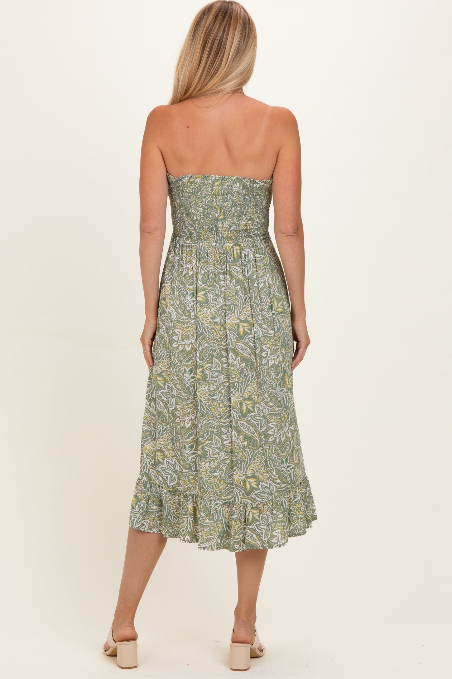 woman wearing a green floral strapless midi dress with a smocked bodice and ruffled hemline, viewed from the back
