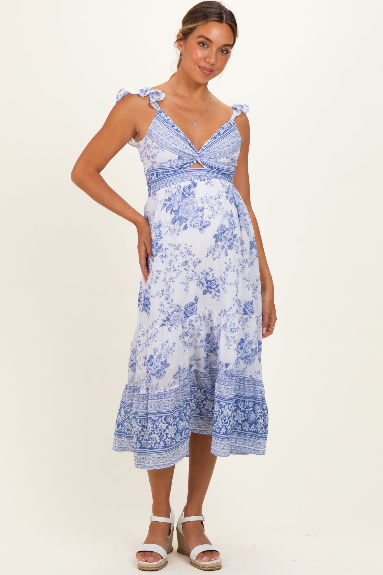 woman wearing a blue and white floral print maternity dress with tie straps and a visible baby bump
