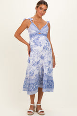 woman wearing a blue and white floral print maternity dress with tie straps and a visible baby bump