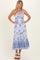 woman wearing a white and blue floral maxi dress with a cutout detail and spaghetti straps